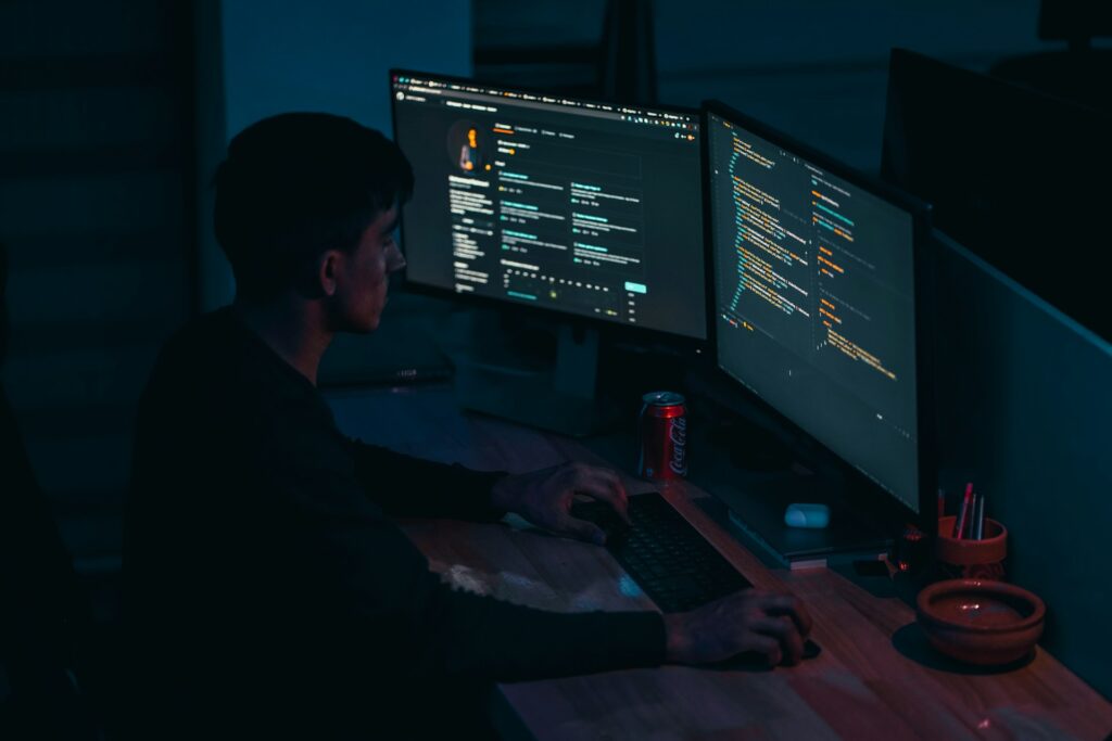 Programador trabalhando em frente ao computador com várias telas de código, representando as carreiras em TI que exigem programação