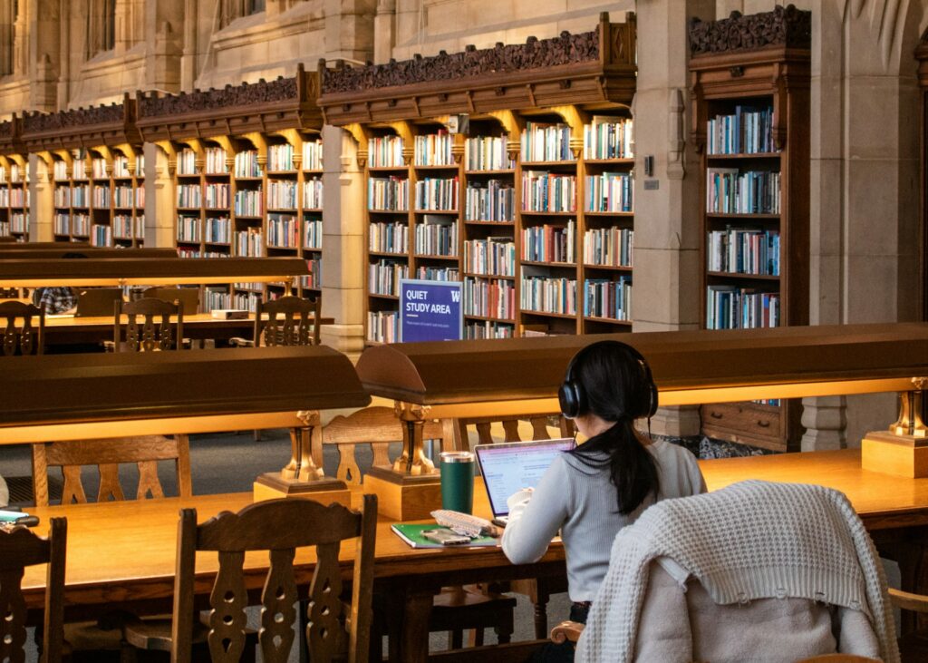 Jovem estudante em ambiente acadêmico utilizando computador, representando o dilema de optar por uma graduação em TI frente às alternativas do mercado